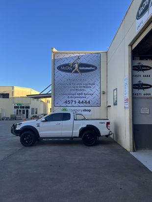White pickup truck parked outside a building with a sign.