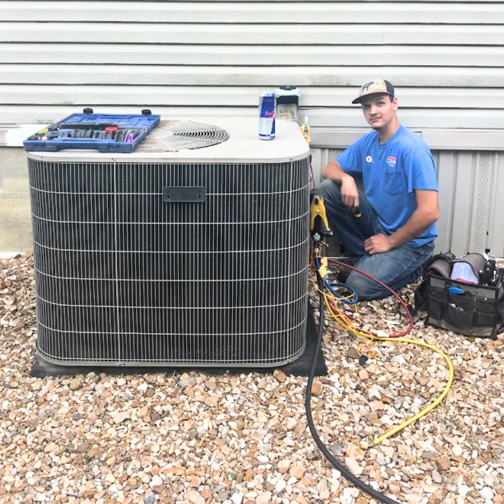 Electrician in a yellow hardhat working on electrical wiring near a window.