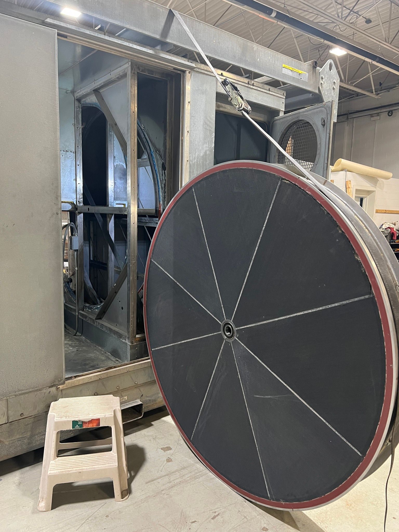 A large wheel is sitting next to a small stool in a room.