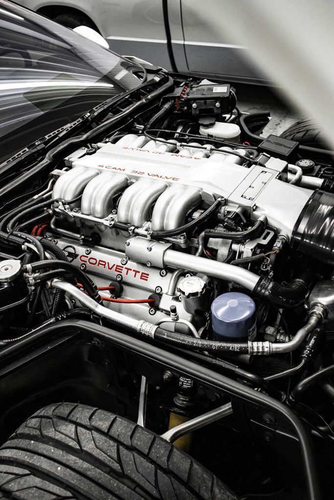 A black Corvette engine bay with a silver V8 engine,