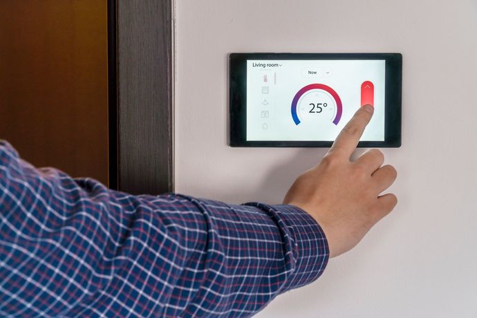 A person is using a smart phone to control a thermostat.