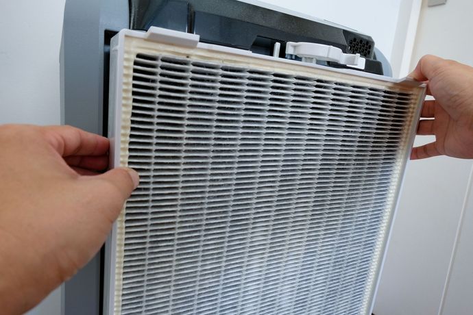 A person is cleaning a filter on an air purifier.