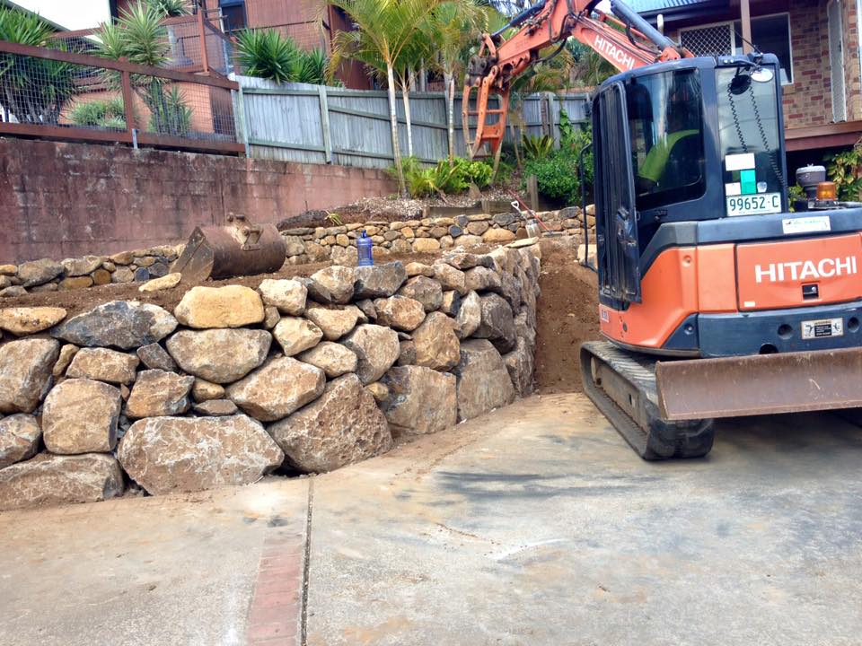 Excavator Piling Up Rocks — Retaining Wall Builders in Northern Rivers, NSW