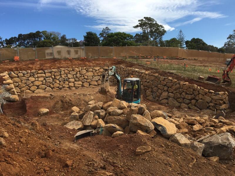 Excavator Moving Rocks — Retaining Wall Builders in Northern Rivers, NSW