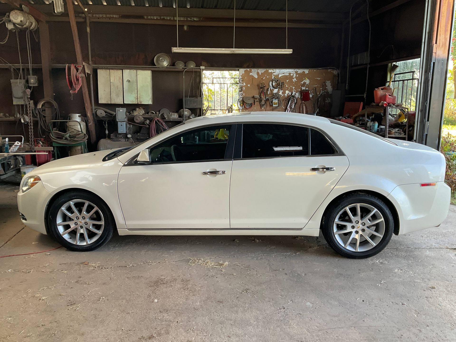 White sedan parked inside a workshop.