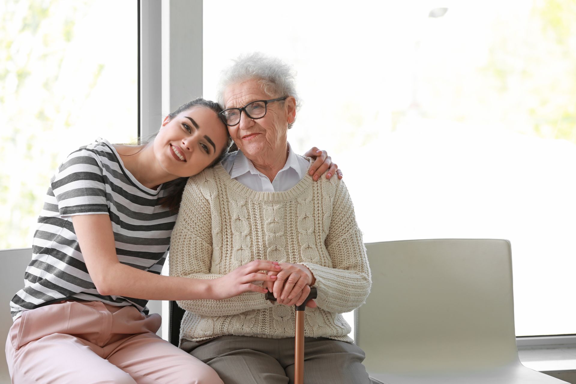 A young woman is hugging an older woman while sitting on a couch.