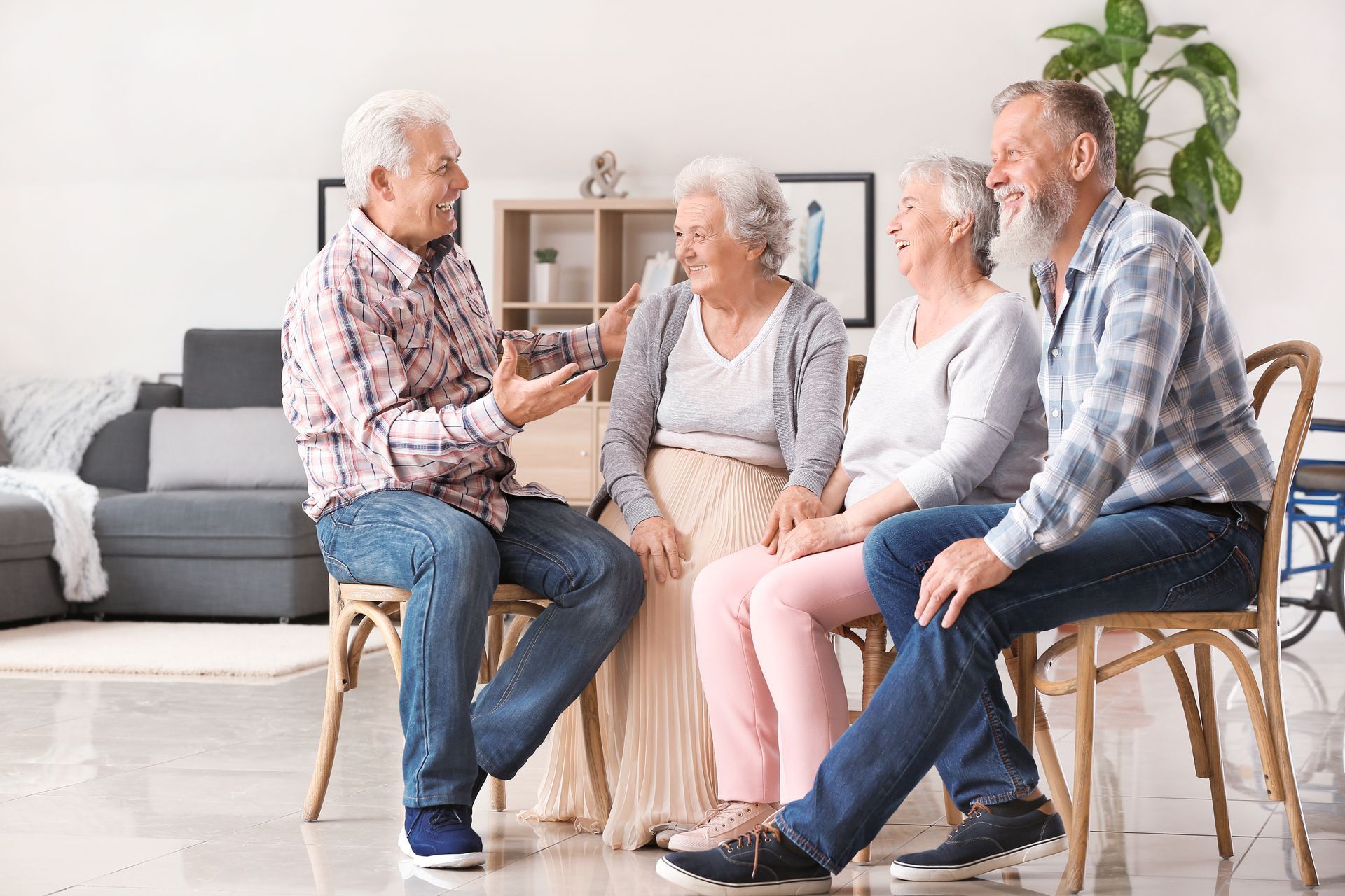 a group of elderly people are sitting on chairs in a living room talking to each other .
