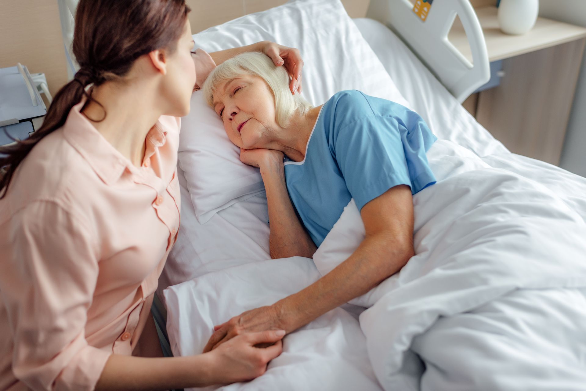 Senior Care:an elderly woman is laying in a hospital bed with a nurse .