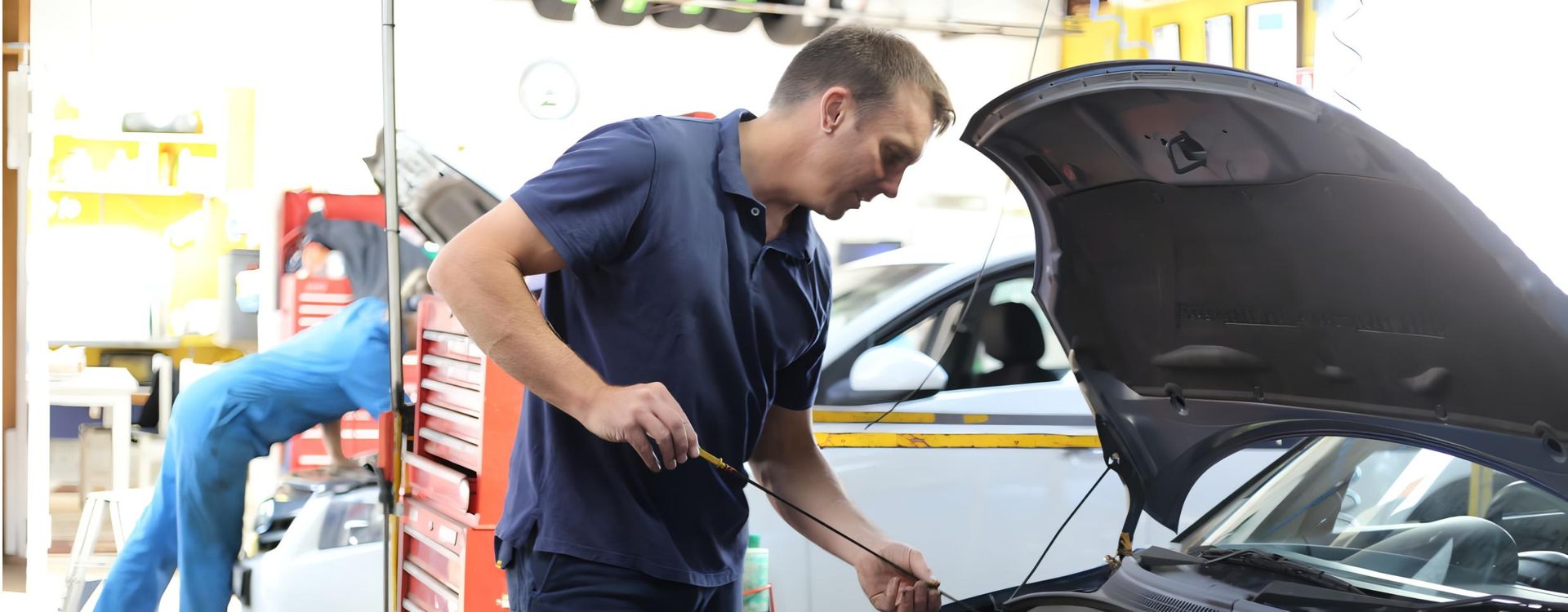 A Man is Working on a Car With the Hood Open in a Garage — CWC Auto Services In Ainslie, ACT