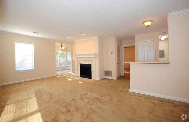 an empty living room with a fireplace and a ceiling fan .