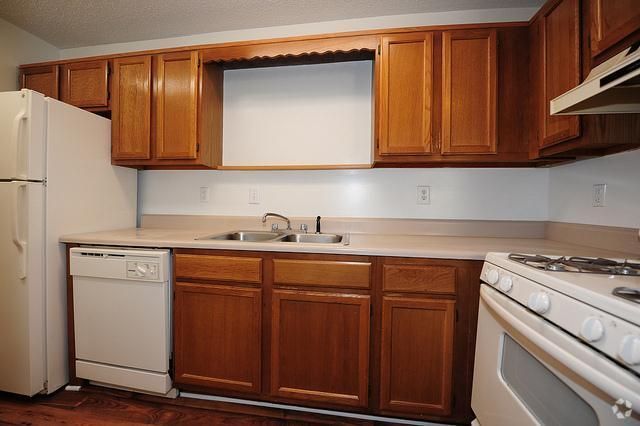 a kitchen with wooden cabinets , a refrigerator , stove , dishwasher and sink .