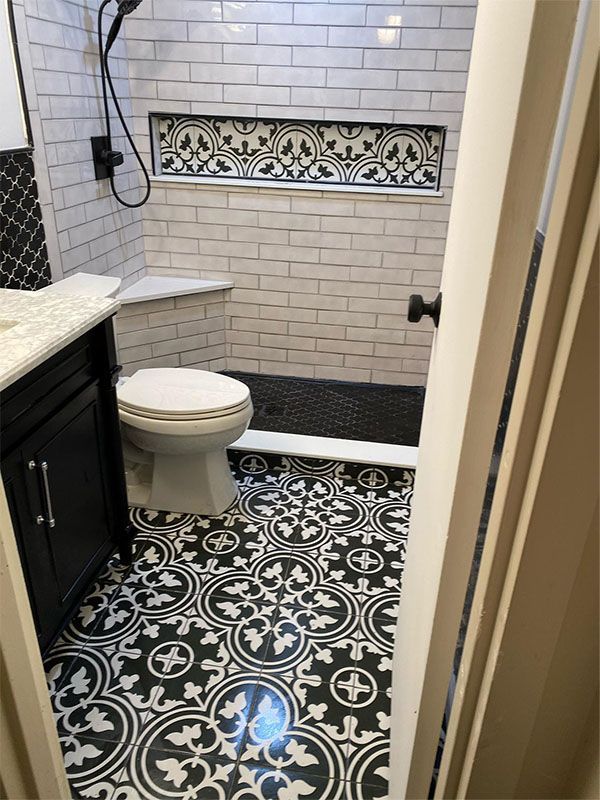 Bathroom with black and white patterned floor tiles, white subway tile shower, and black vanity.