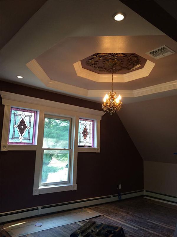 Room with burgundy walls, stained glass windows, and ornate chandelier. Ceiling has decorative trim.