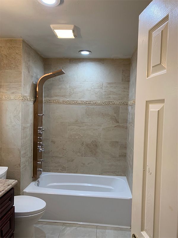Bathroom with a bathtub, shower fixture, and beige tile walls.