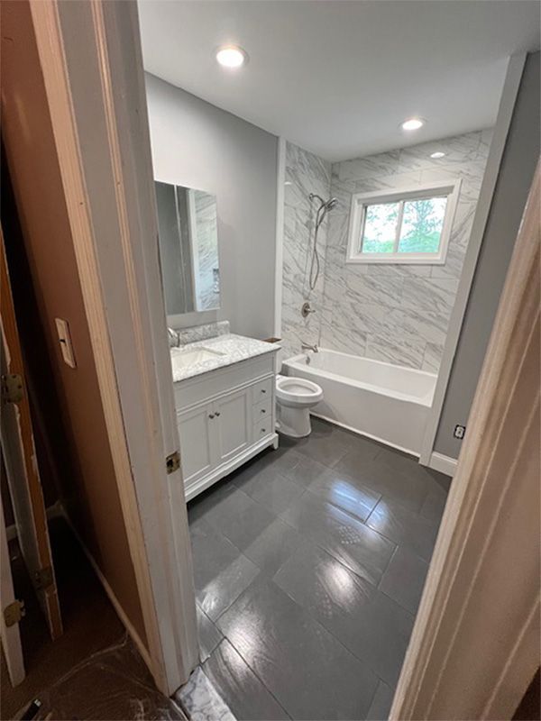 Bathroom with gray walls, white vanity, marble tile, and dark gray floor.