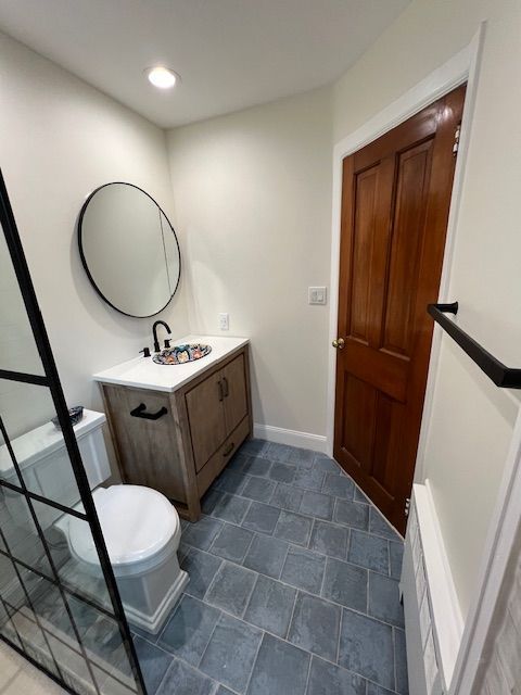 Bathroom with a wooden vanity, round mirror, and blue tiled floor.