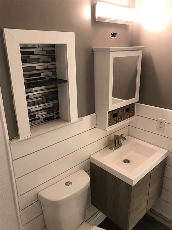 Bathroom with a white toilet, vanity, and a recessed shelf with mosaic tile.