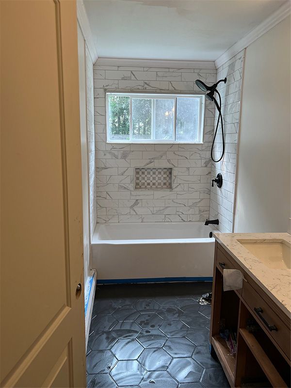 Bathroom with white marble tile, black fixtures, hexagon floor tiles, and wood vanity.