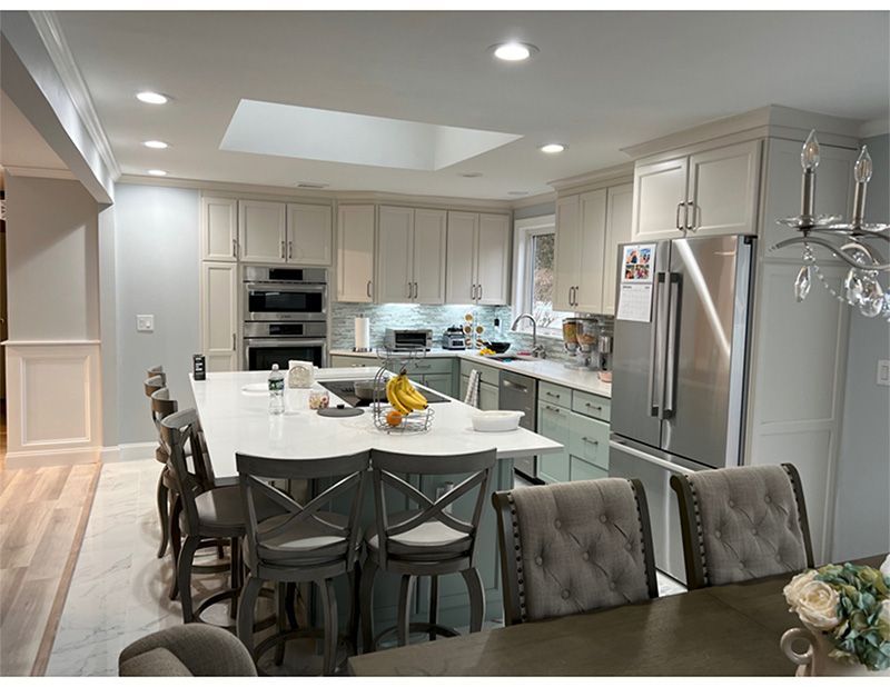 Modern kitchen with island, cabinets, appliances, and bar stools. Bright with overhead lighting.