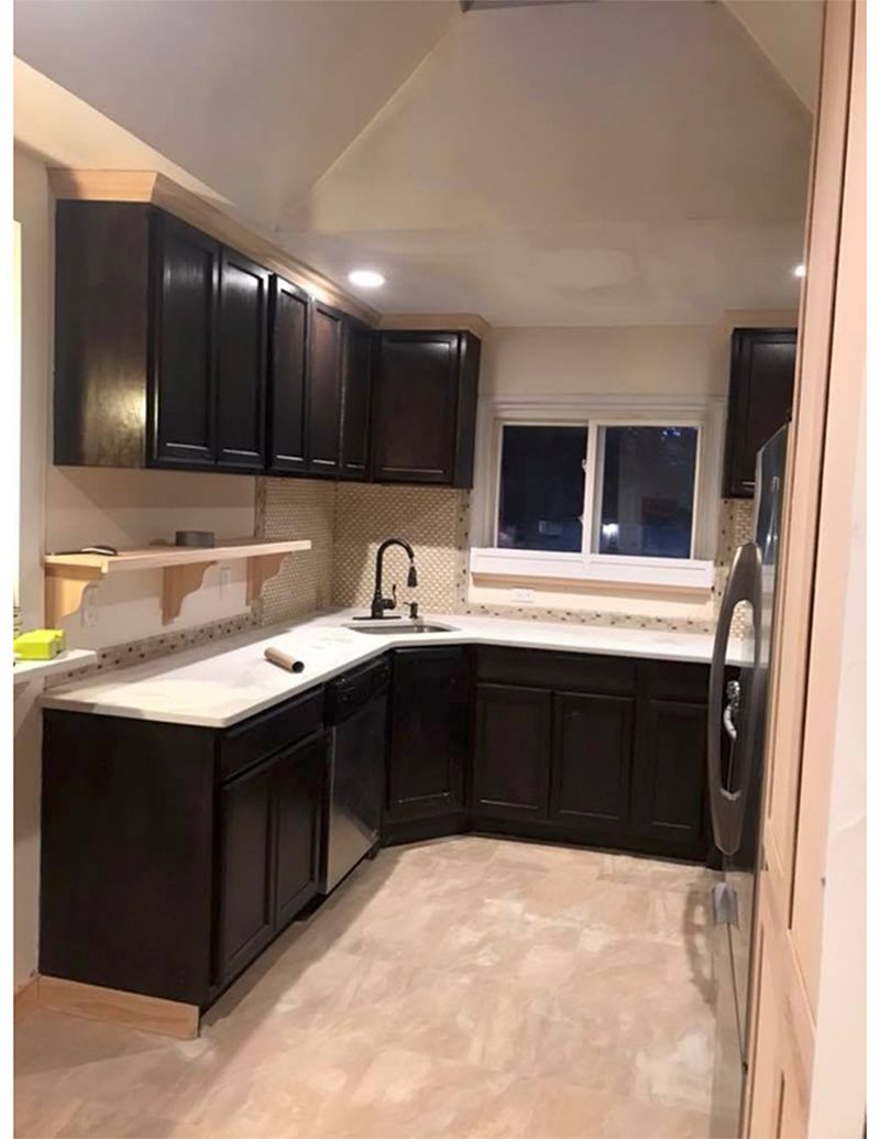 Dark brown kitchen cabinets, light countertops, window, and sink in a newly renovated kitchen.