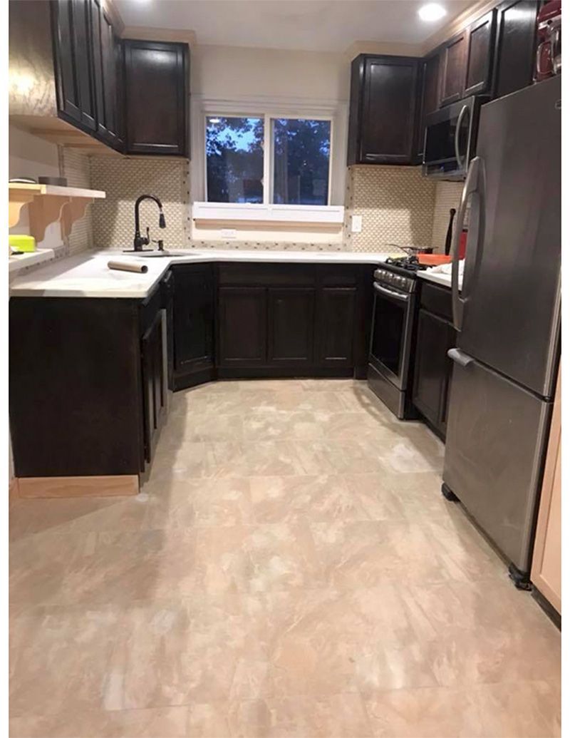Dark-brown kitchen cabinets and light-colored countertops with a stainless steel refrigerator and stove.