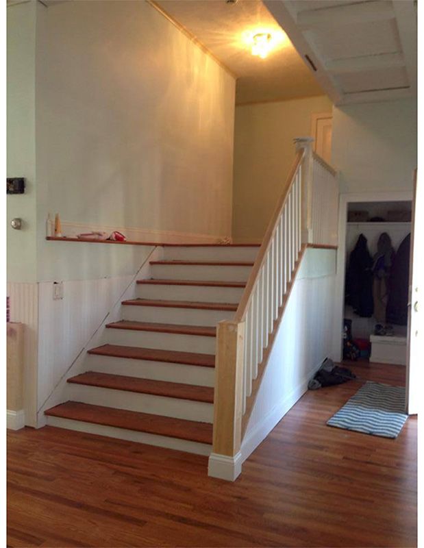 Interior shot of stairs with wooden steps, white railing and walls, leading up to a landing.