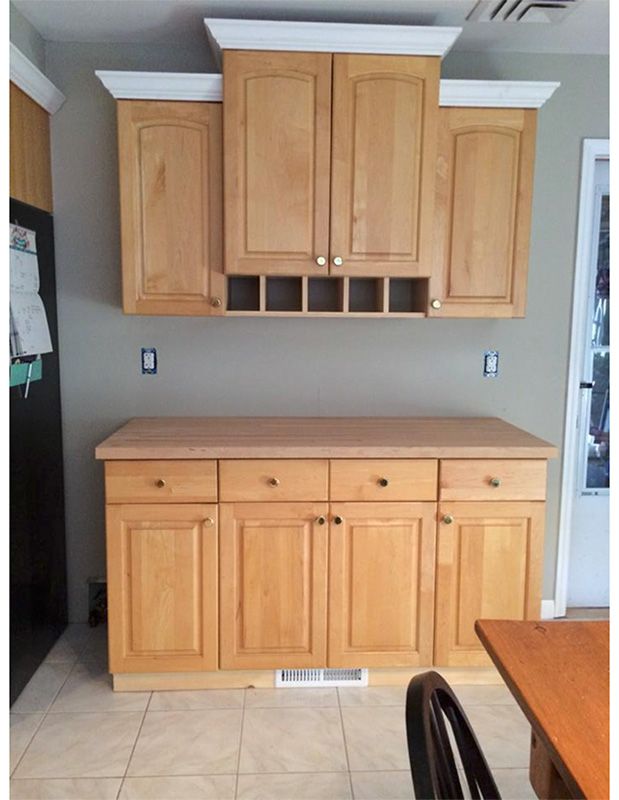 Wooden kitchen cabinets on a gray wall, including upper cabinets, a wine rack, and a counter with lower cabinets.