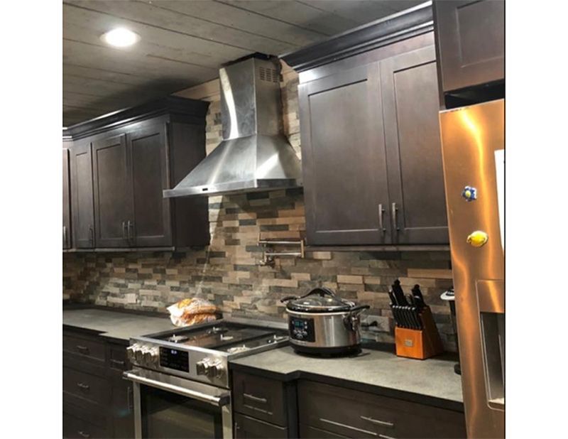 Kitchen with dark brown cabinets, stainless steel range hood, and stove.