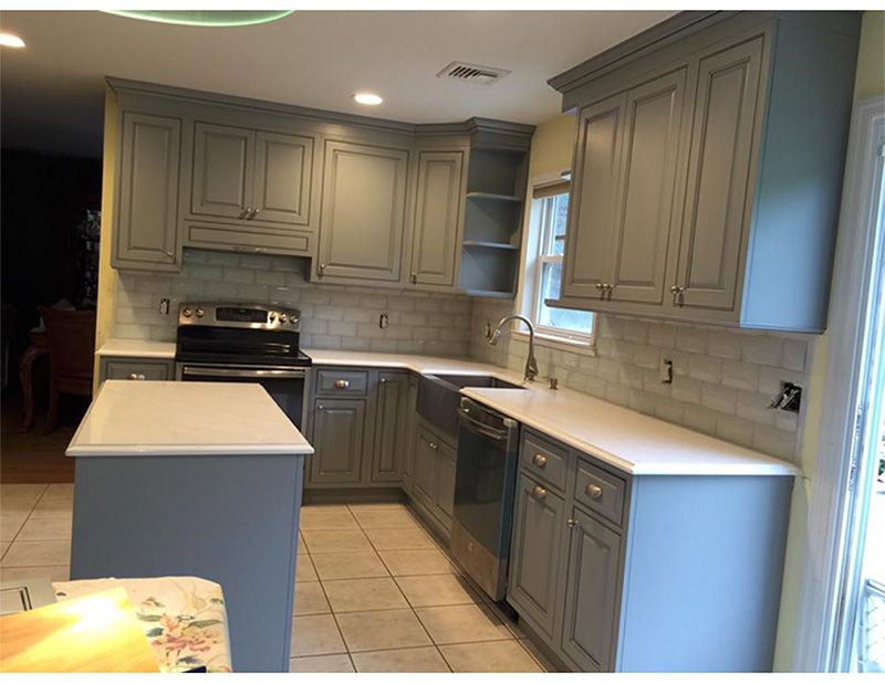 Grey kitchen cabinets and white countertops in a remodeled kitchen.