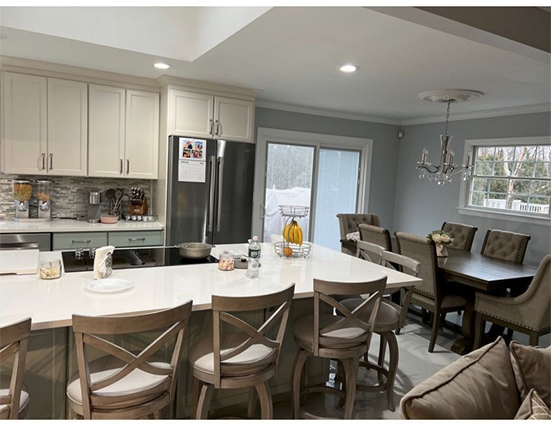 Spacious kitchen with a large island and dining area. Neutral colors. Stainless steel appliances, window, and sliding door.