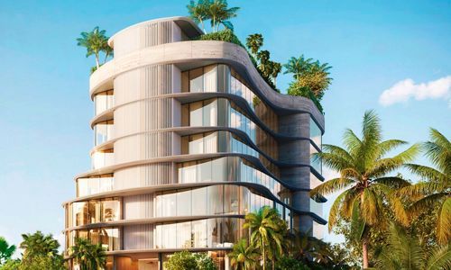 Modern curved white apartment building with balconies, surrounded by palm trees under a blue sky