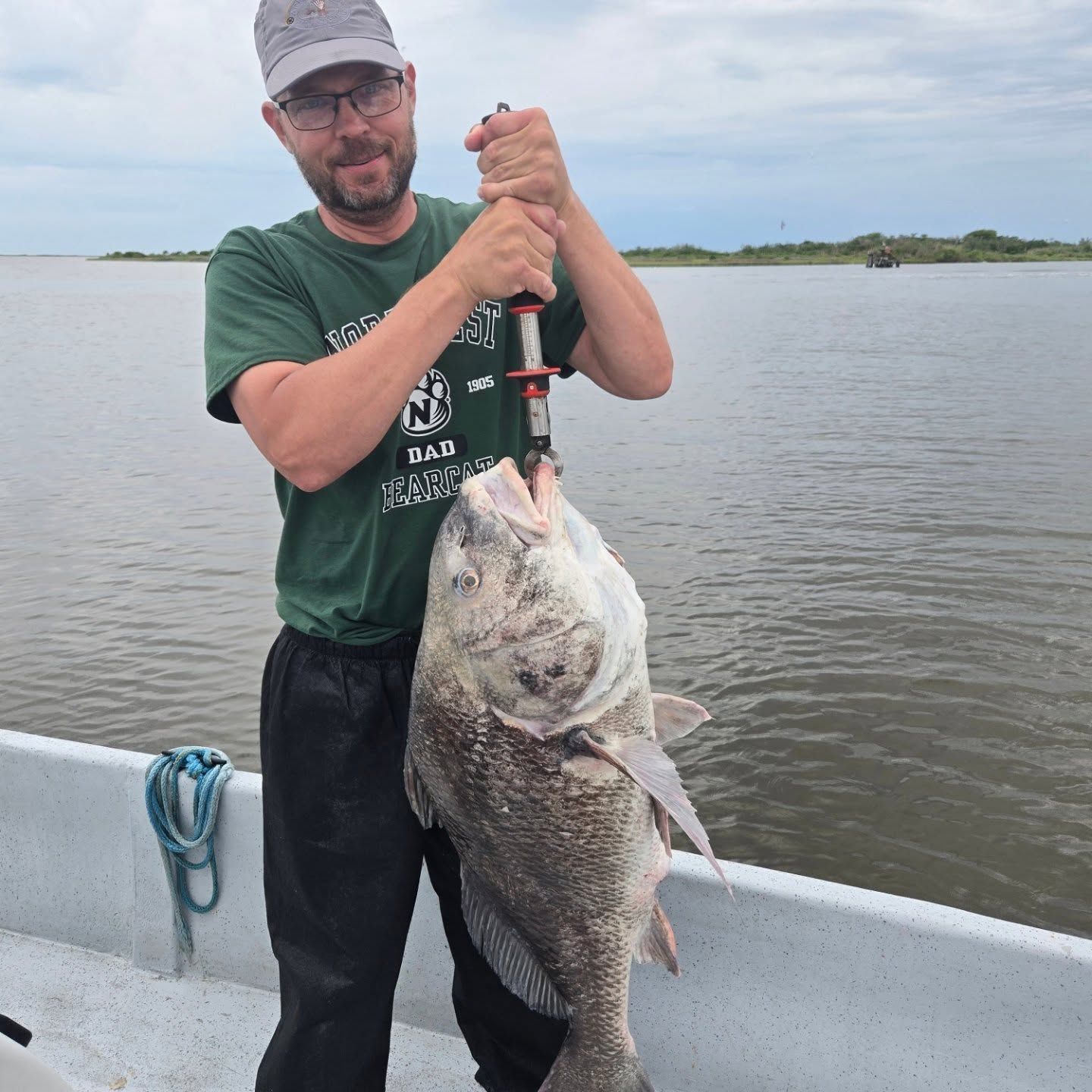 Man holding a large fish on a boat over calm water