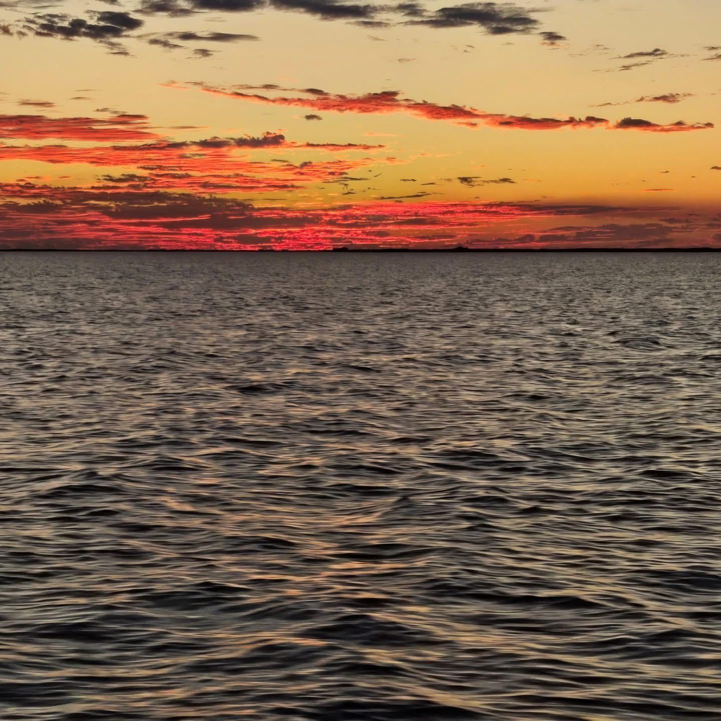 Sunset over calm rippling ocean with red-orange clouds