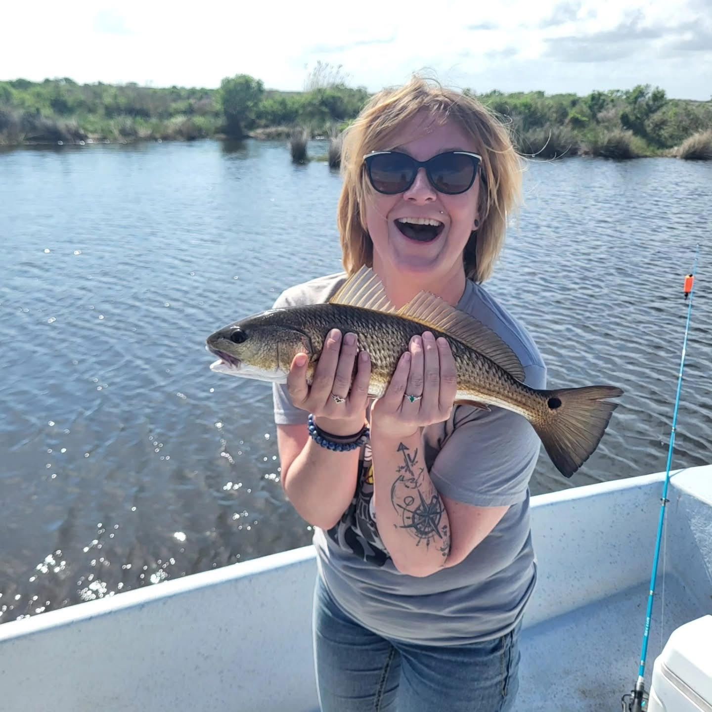 Woman smiling and holding a fish on a boat on calm water
