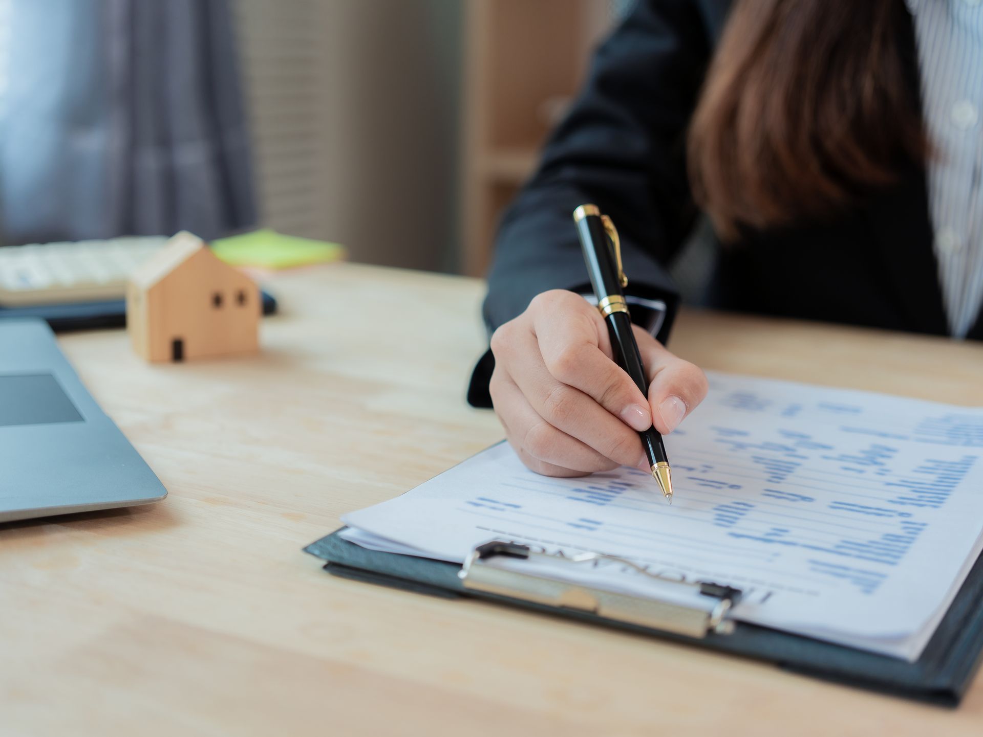 Woman with older couple at a table, looking at documents and a tablet. Interior setting with bookshelf.