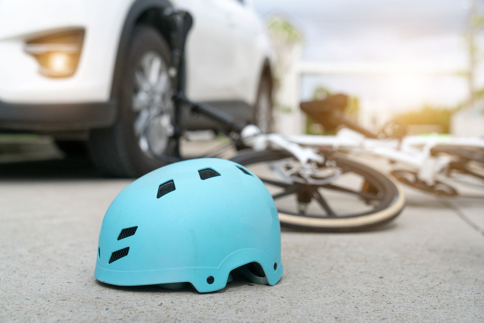 Blue helmet on pavement, bicycle and car in background, likely indicating a collision.