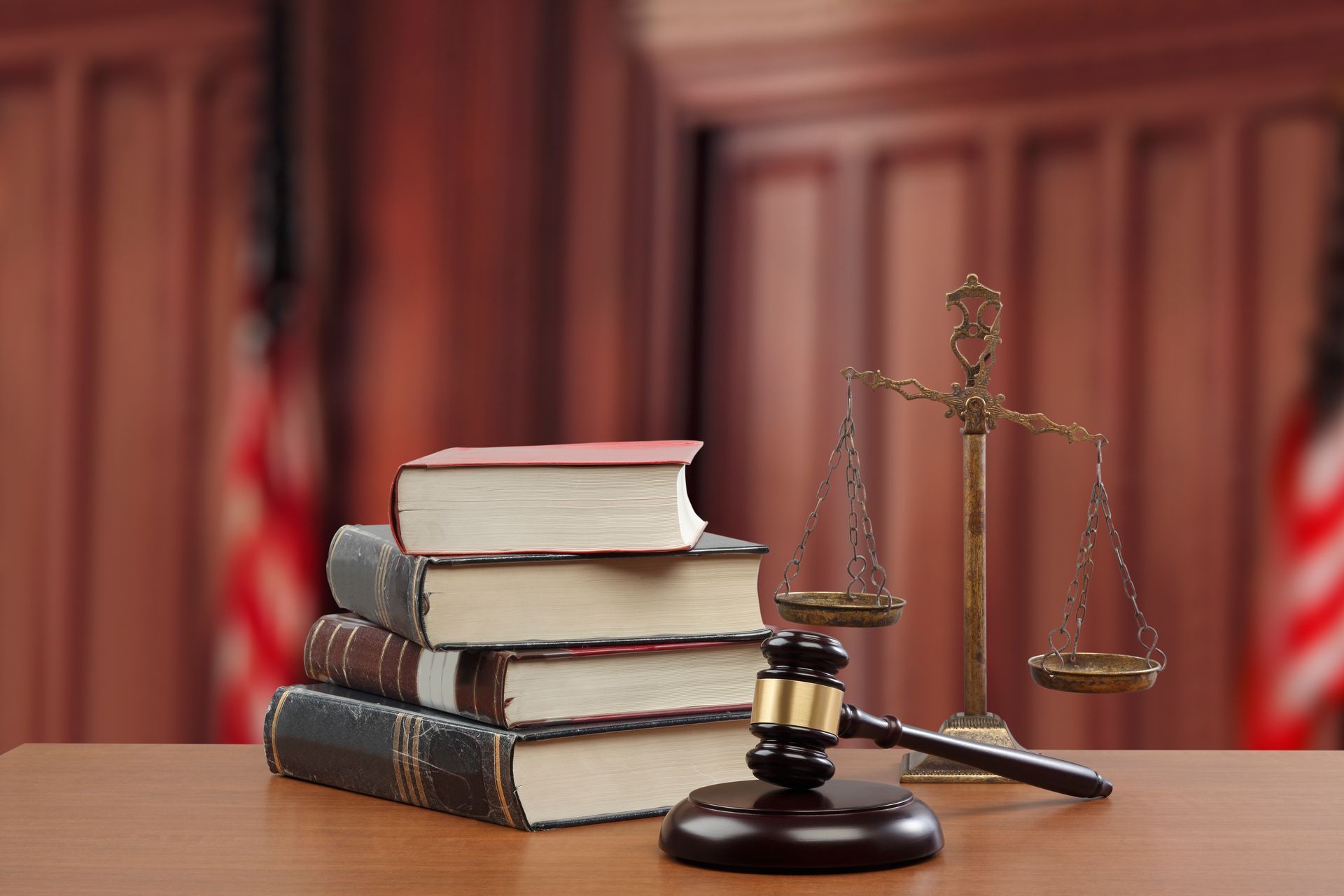 Books, scales of justice, and gavel on a desk in a courtroom.