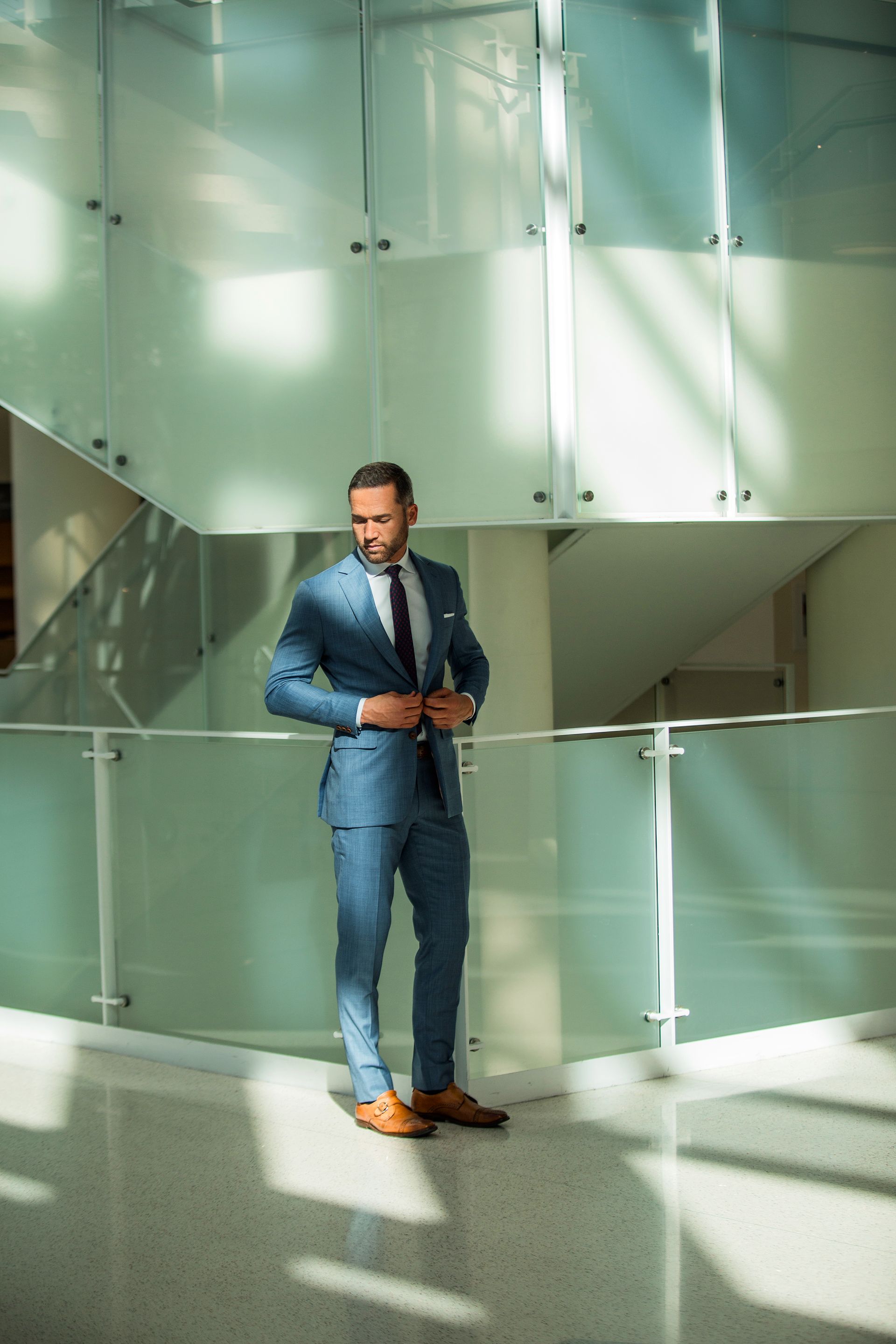 A man in a blue suit and tie is standing in a hallway.