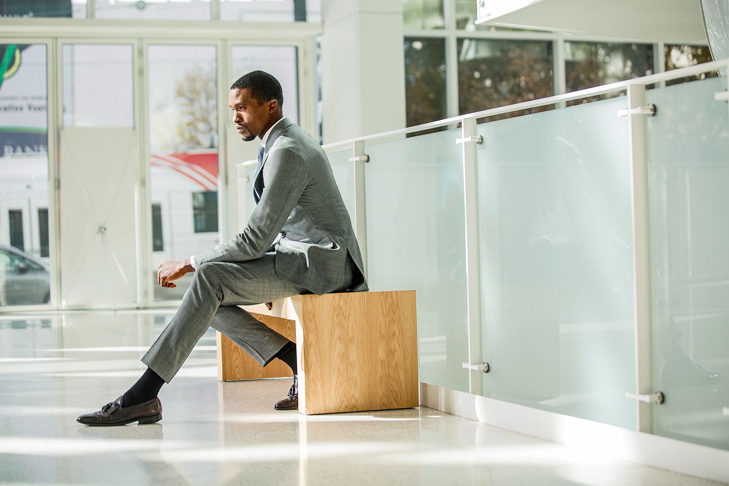 a man in a suit is sitting on a wooden bench .