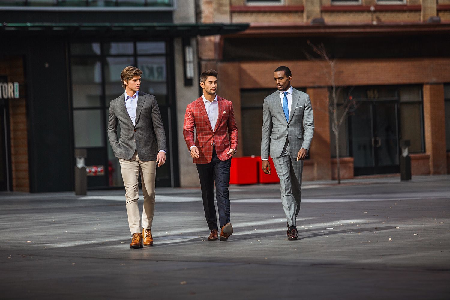 Three men in suits are walking down a city street.