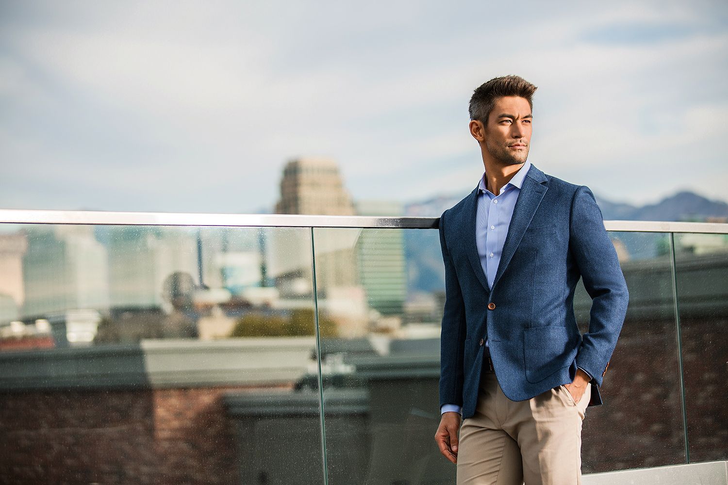 A man in a suit is standing on a balcony overlooking a city.
