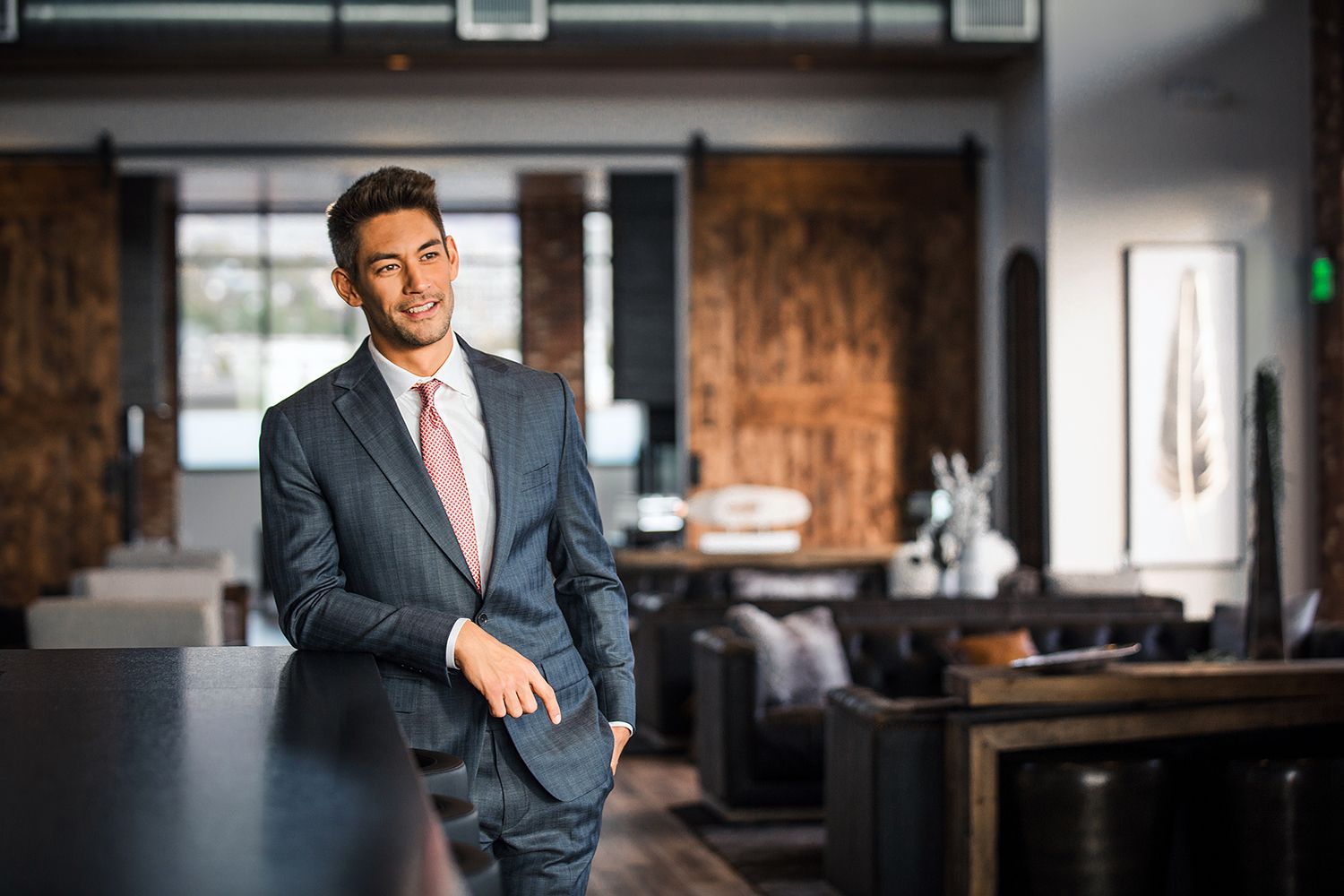 A man in a suit and tie is standing in a room with his hands in his pockets.