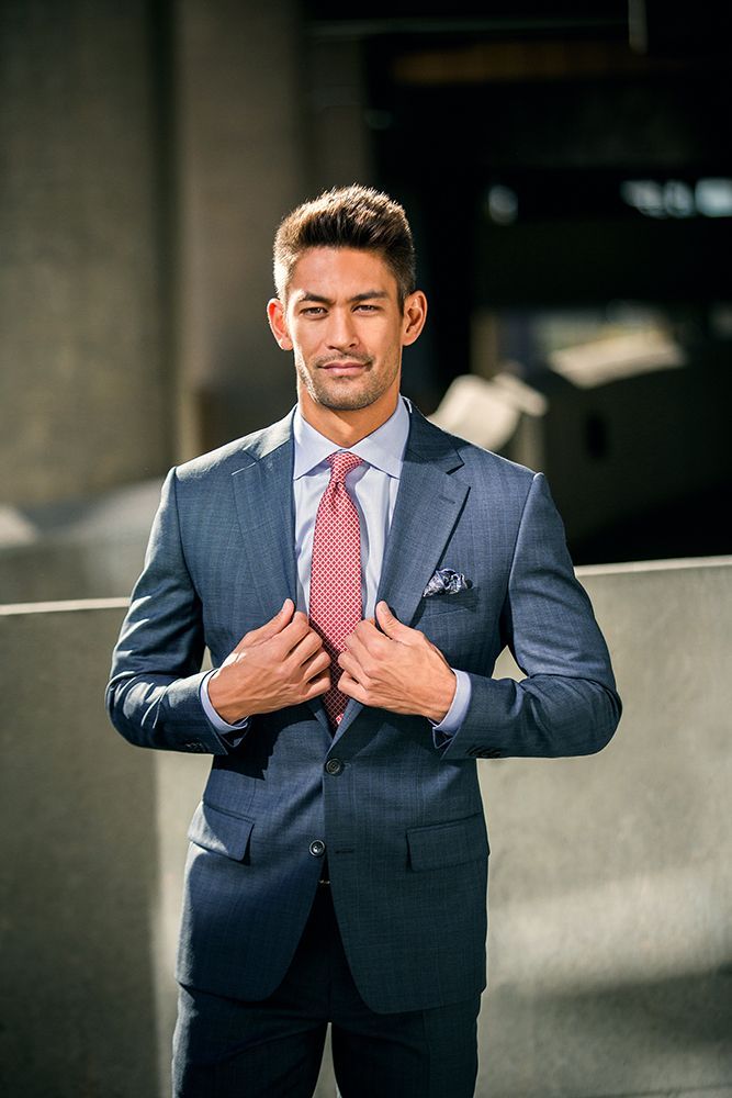 A man in a suit and tie is adjusting his tie.