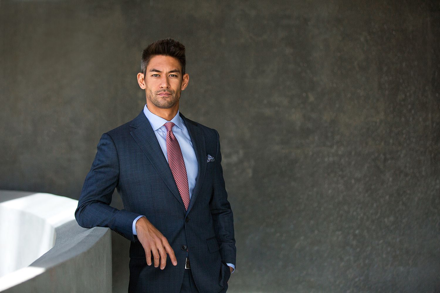 a man in a suit and tie is leaning against a wall .