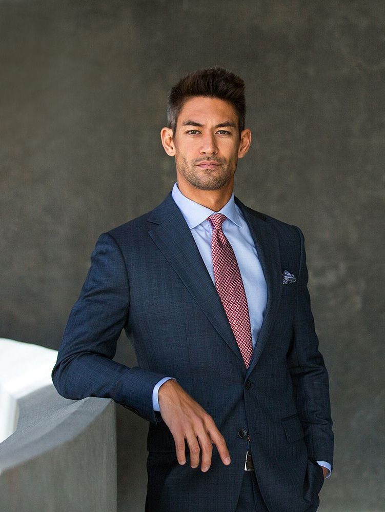 a man in a suit and tie is leaning against a wall .