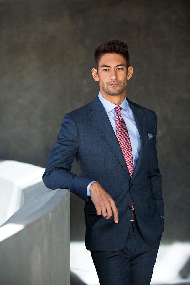 A man in a suit and tie is leaning against a wall.