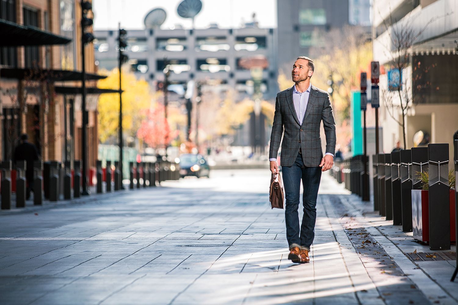 A man in a suit is walking down a city street with a briefcase.