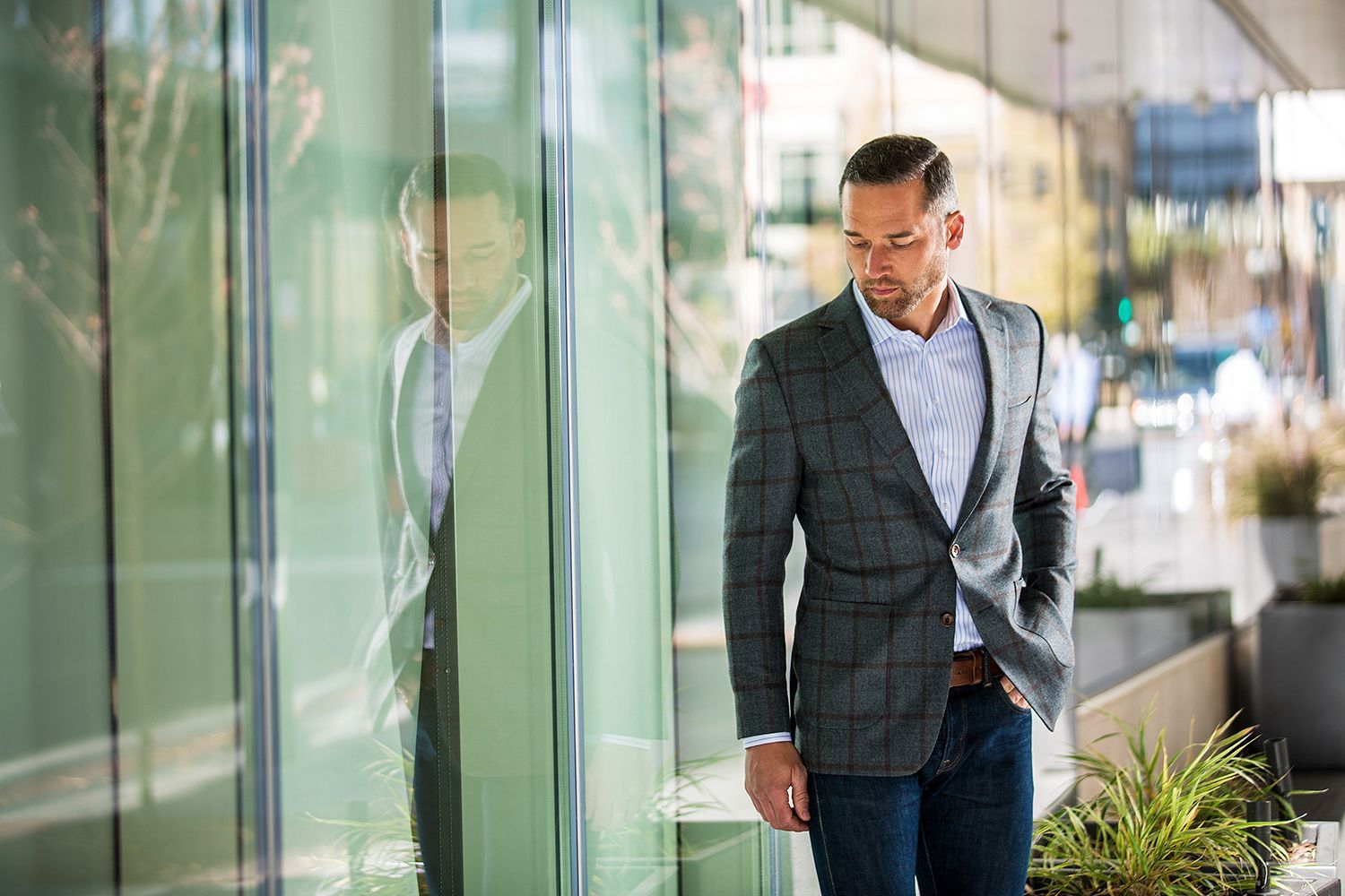 a man in a suit is standing in front of a glass building .