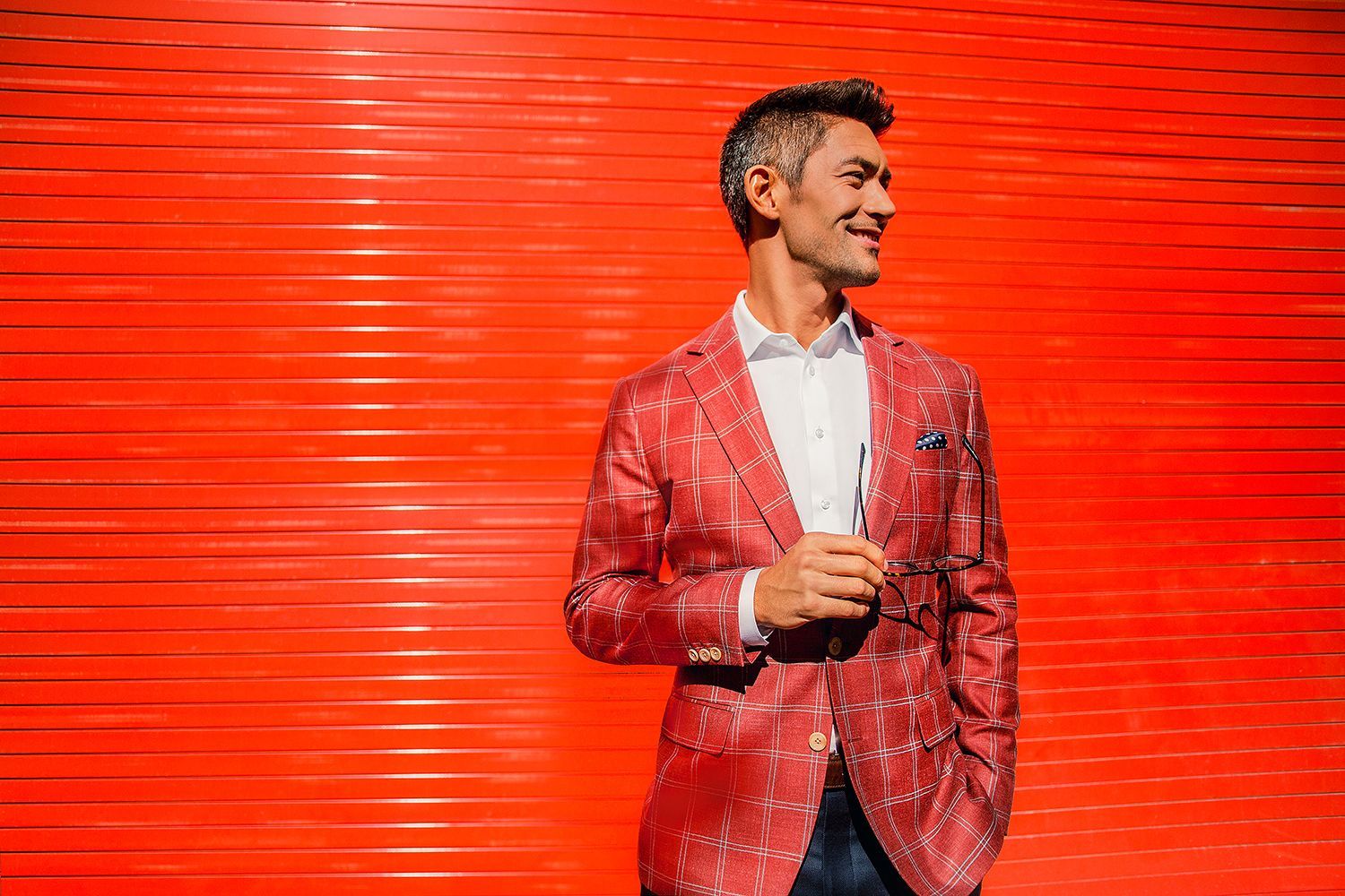 a man in a red suit is standing in front of a red wall .