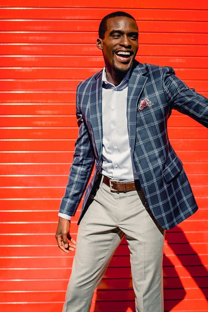 a man in a suit is standing in front of a red wall .